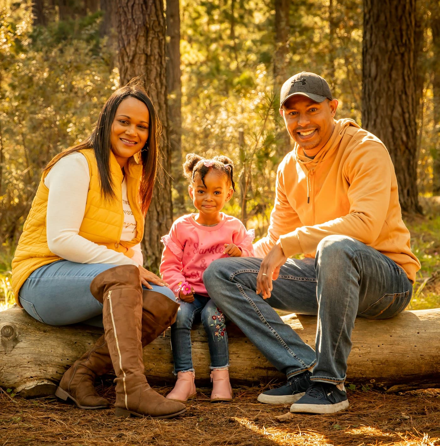 Pai, mãe e filha sentados juntos em um parque